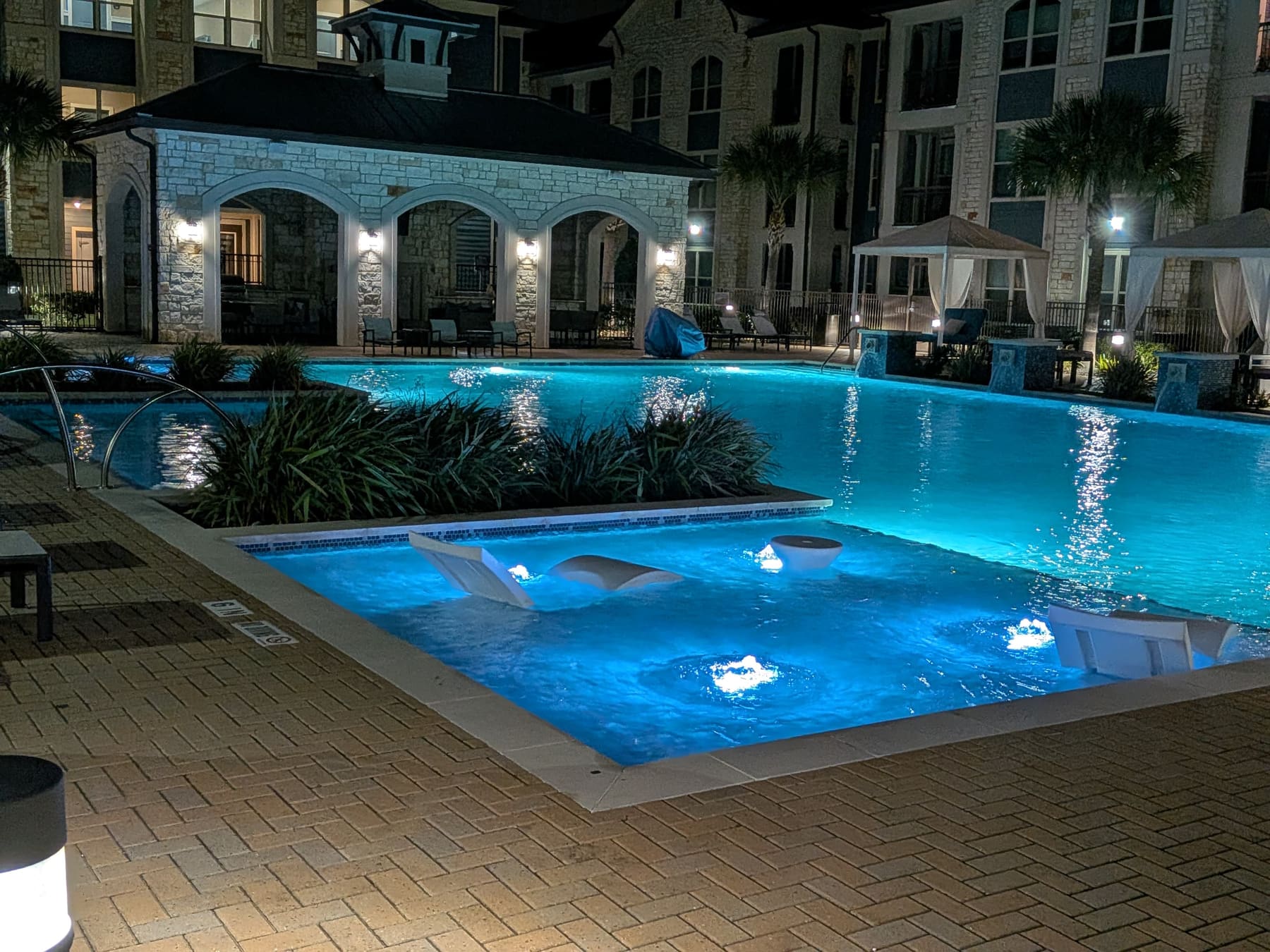 Resort-style community pool with cabanas lit at night