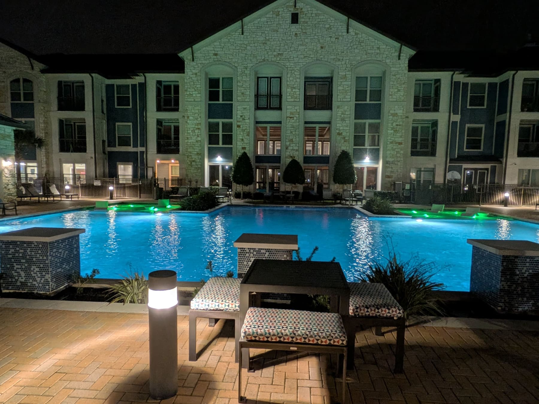 Community pool with green accent lighting and patio seating